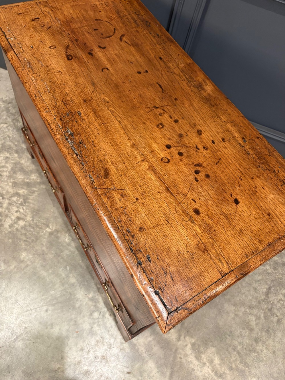 A Georgian elm blanket box featuring a hinged top lid, two lower drawers with brass swan-neck handles, and shaped bracket feet. View IX
