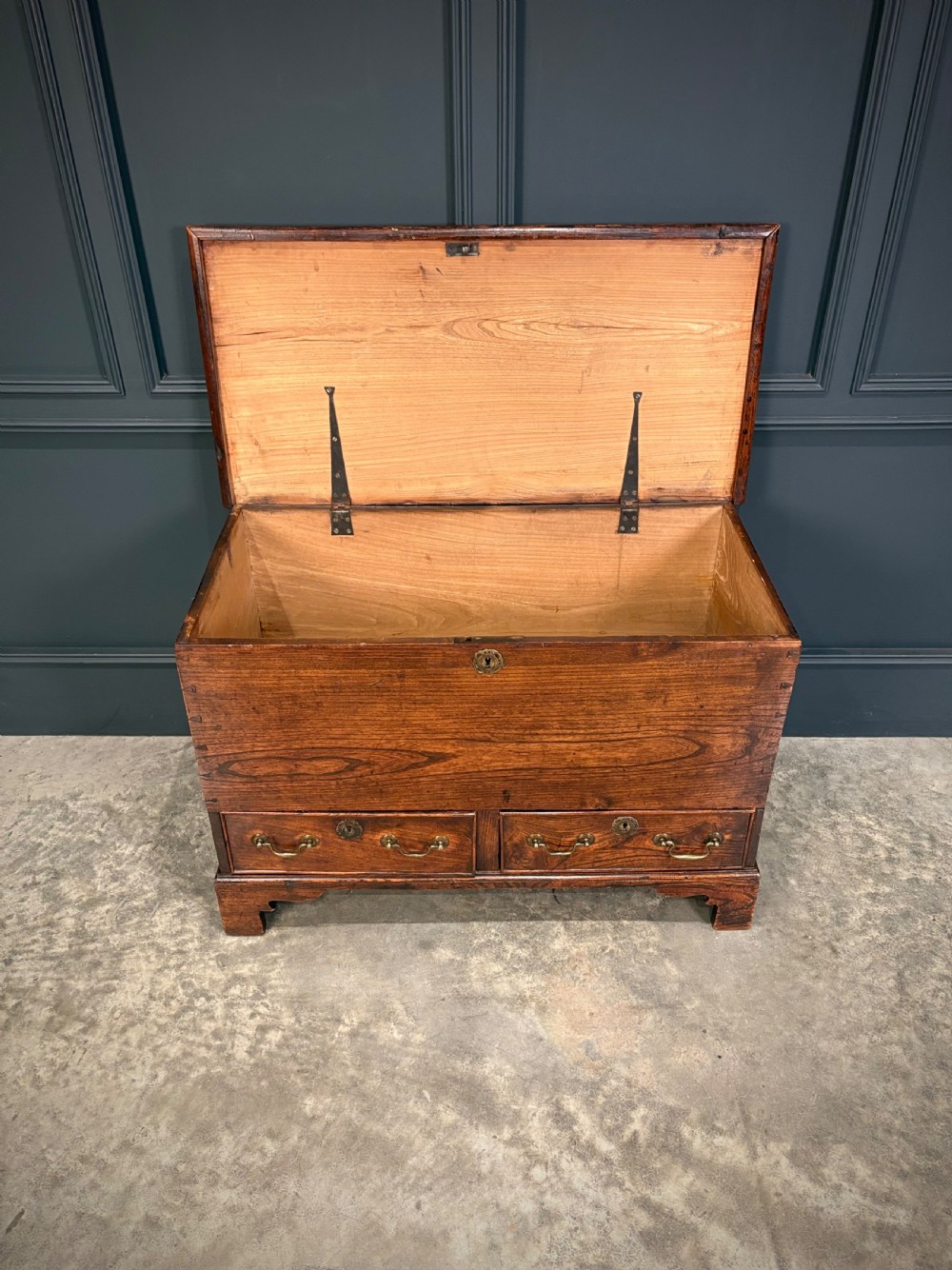A Georgian elm blanket box featuring a hinged top lid, two lower drawers with brass swan-neck handles, and shaped bracket feet. View X