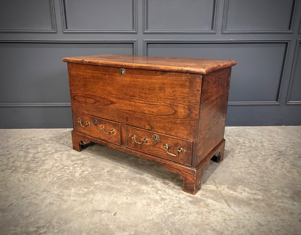 A Georgian elm blanket box featuring a hinged top lid, two lower drawers with brass swan-neck handles, and shaped bracket feet. View XIII