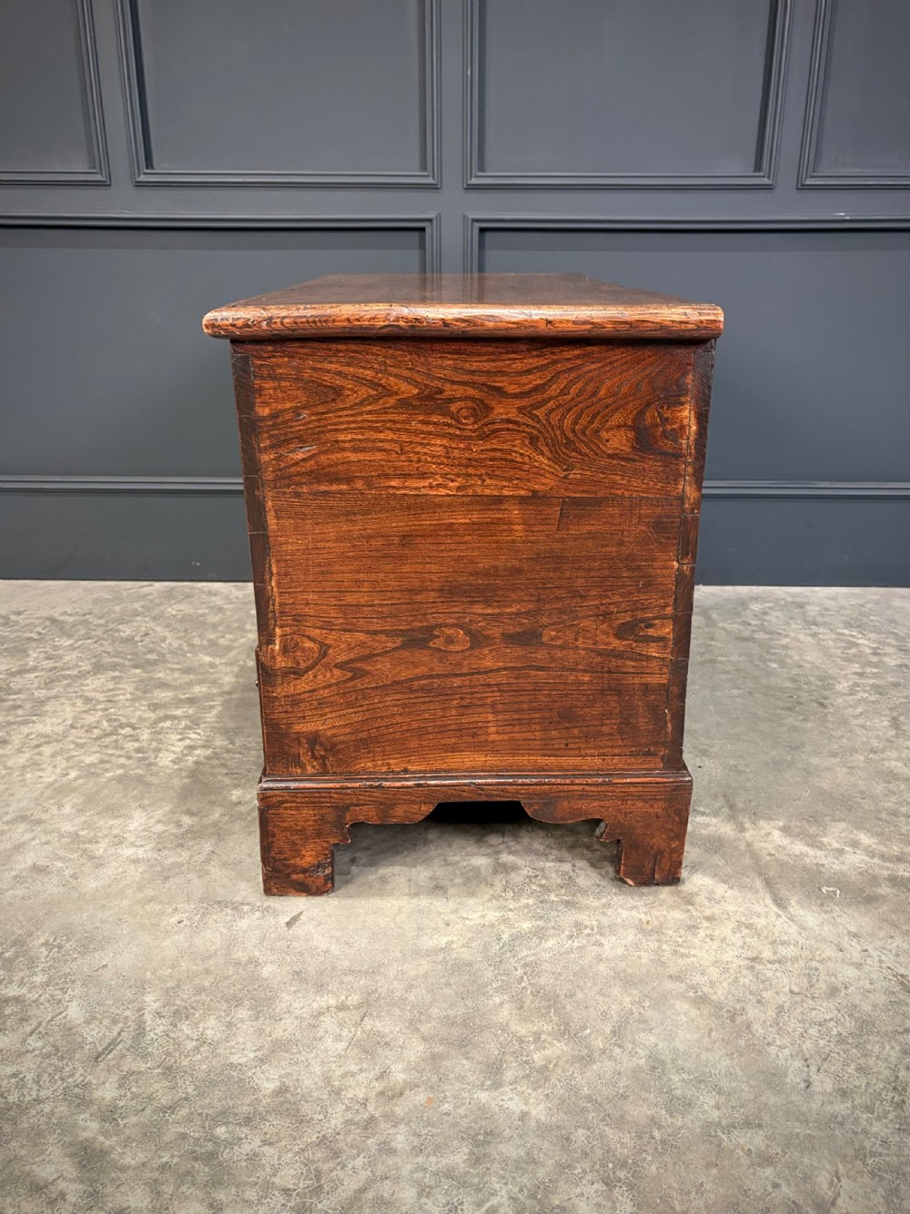 A Georgian elm blanket box featuring a hinged top lid, two lower drawers with brass swan-neck handles, and shaped bracket feet. View XIV
