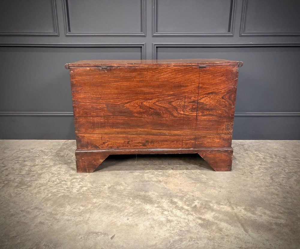 A Georgian elm blanket box featuring a hinged top lid, two lower drawers with brass swan-neck handles, and shaped bracket feet. View XV