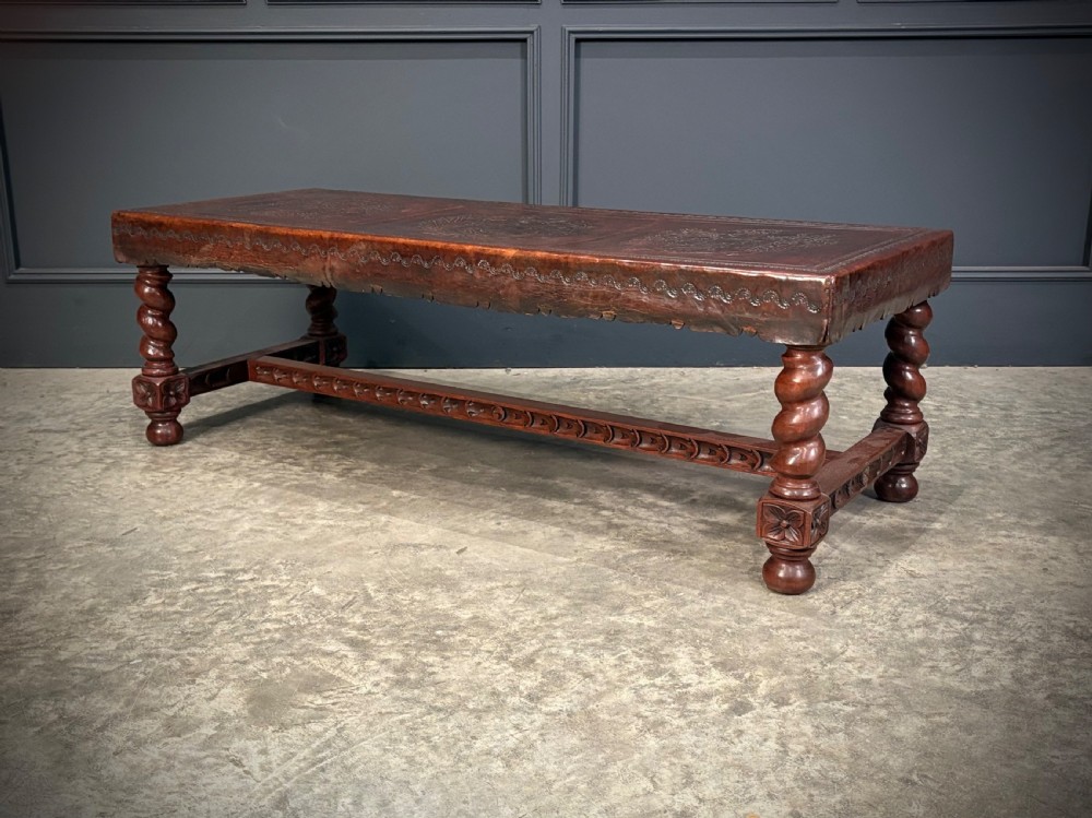 A low rectangular mahogany coffee table featuring three embossed leather top panels depicting heraldic coats of arms and supported by turned legs. View VI