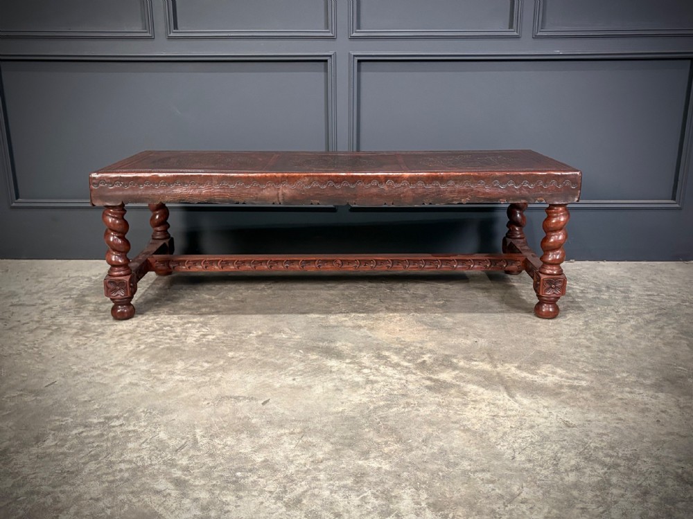 A low rectangular mahogany coffee table featuring three embossed leather top panels depicting heraldic coats of arms and supported by turned legs. View VII