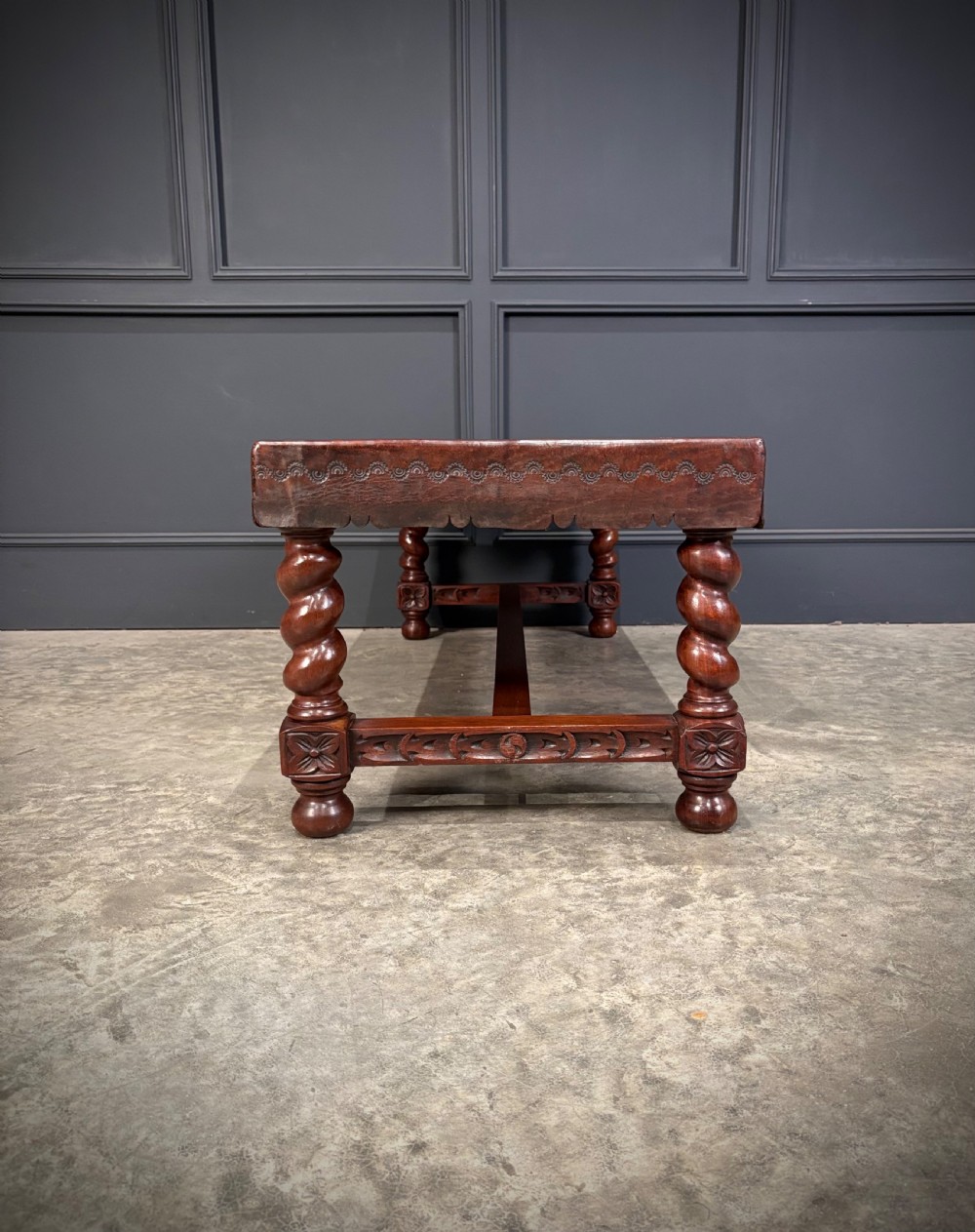 A low rectangular mahogany coffee table featuring three embossed leather top panels depicting heraldic coats of arms and supported by turned legs. View VIII