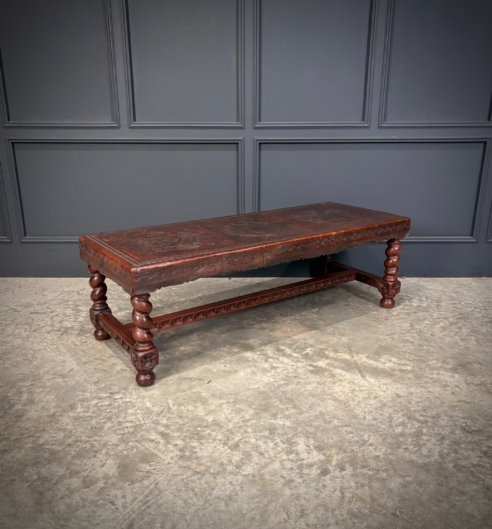 A low rectangular mahogany coffee table featuring three embossed leather top panels depicting heraldic coats of arms and supported by turned legs. View XI