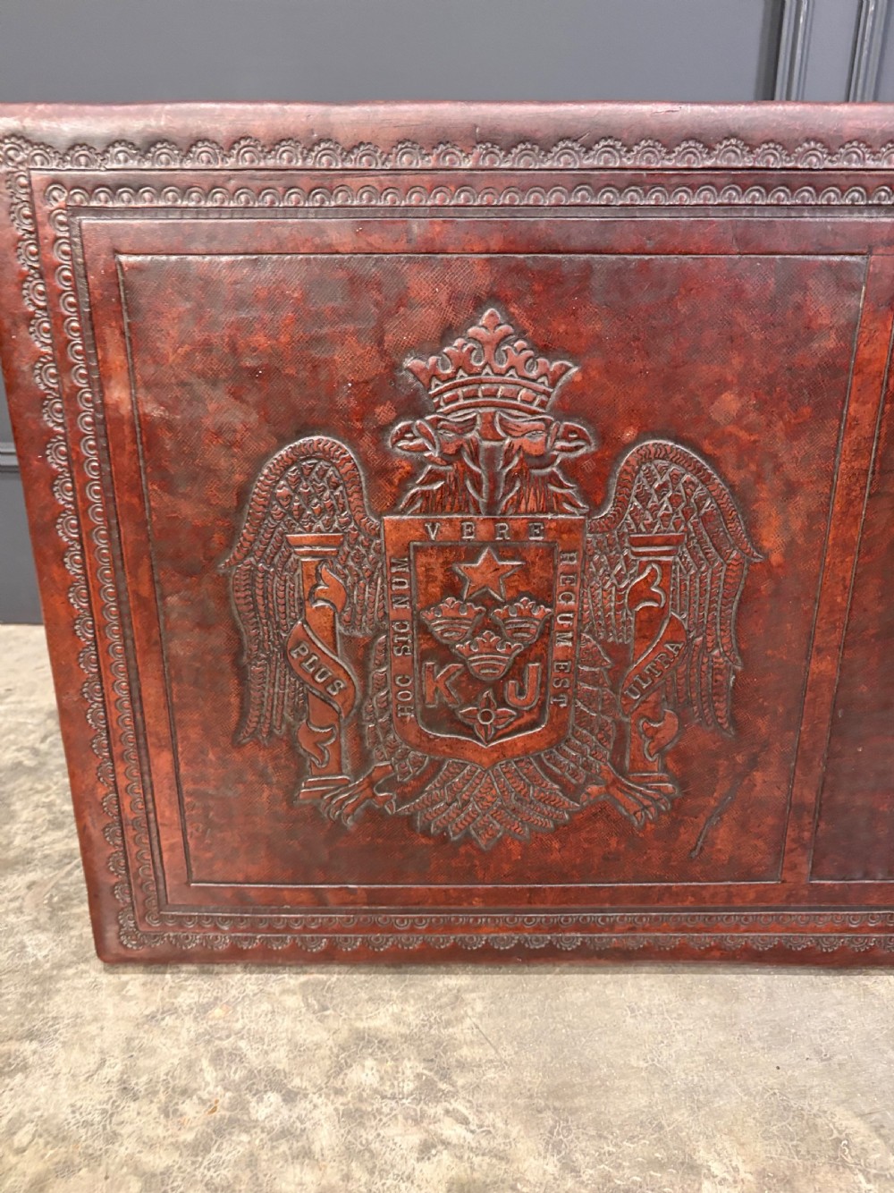 A low rectangular mahogany coffee table featuring three embossed leather top panels depicting heraldic coats of arms and supported by turned legs. View XIII
