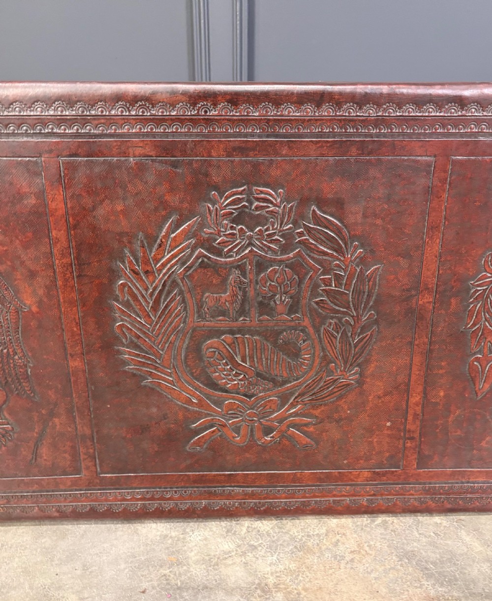A low rectangular mahogany coffee table featuring three embossed leather top panels depicting heraldic coats of arms and supported by turned legs. View XIV