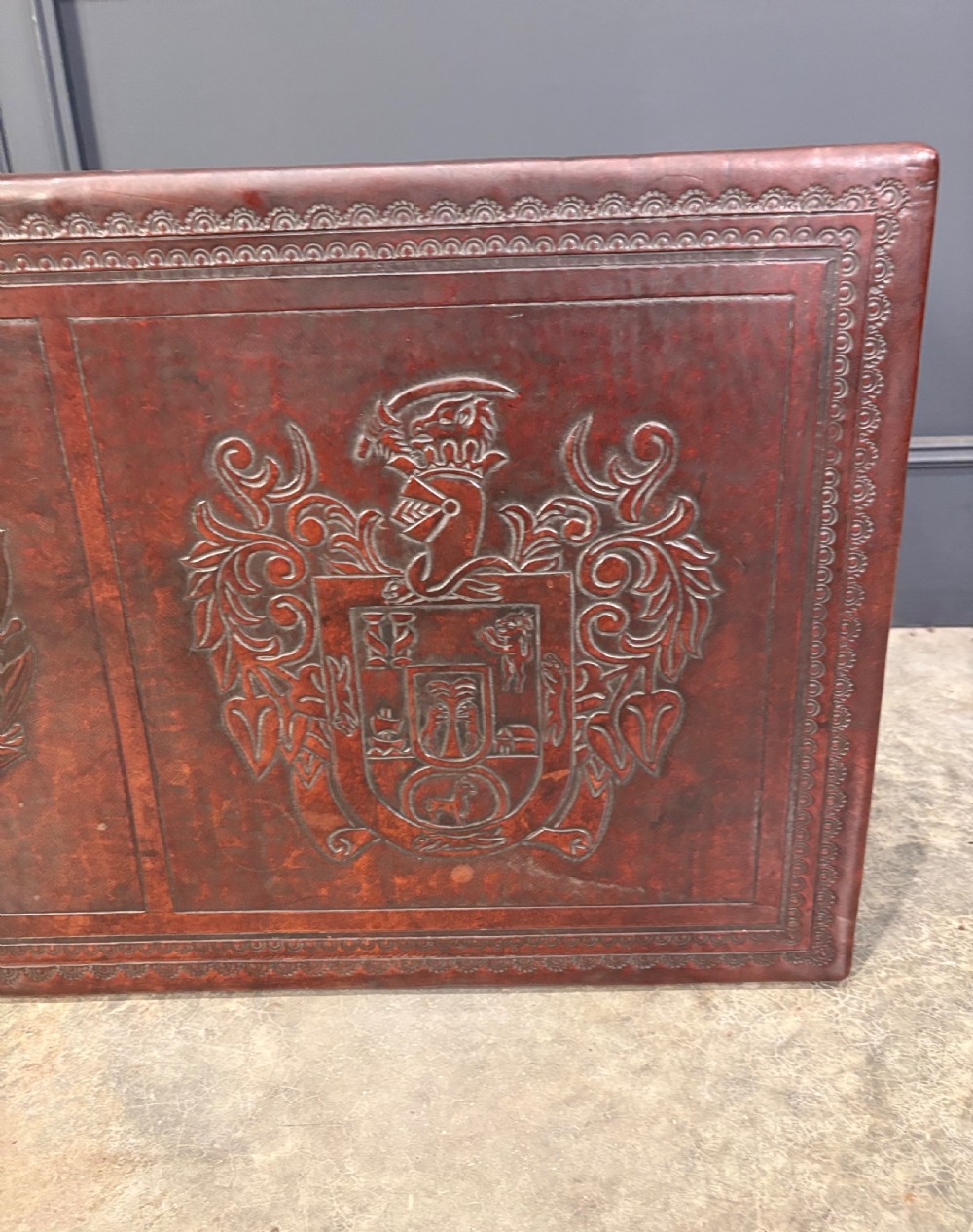 A low rectangular mahogany coffee table featuring three embossed leather top panels depicting heraldic coats of arms and supported by turned legs. View XV