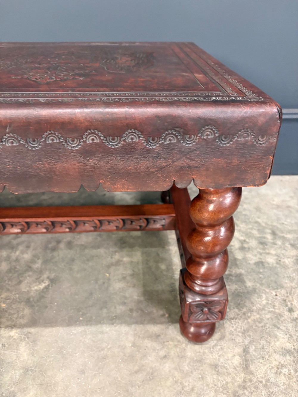 A low rectangular mahogany coffee table featuring three embossed leather top panels depicting heraldic coats of arms and supported by turned legs. View XVII