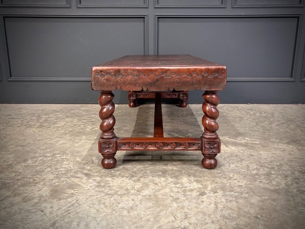 A low rectangular mahogany coffee table featuring three embossed leather top panels depicting heraldic coats of arms and supported by turned legs. View XVIII