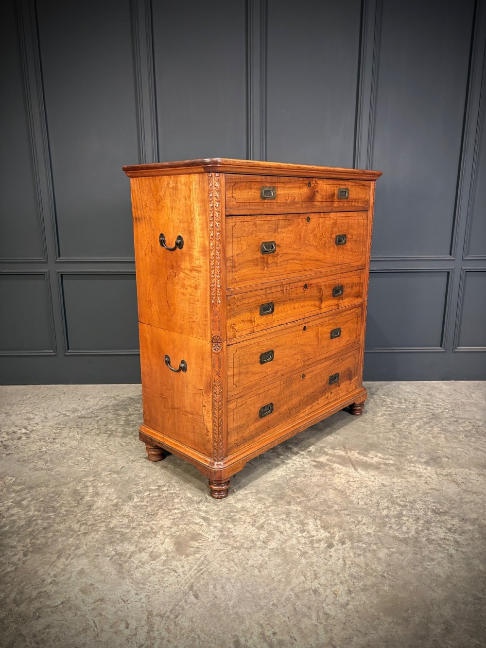 A 19th-century camphor wood campaign secretaire chest featuring a two-part split construction with flush brass handles, side carrying handles, and carved pilasters.