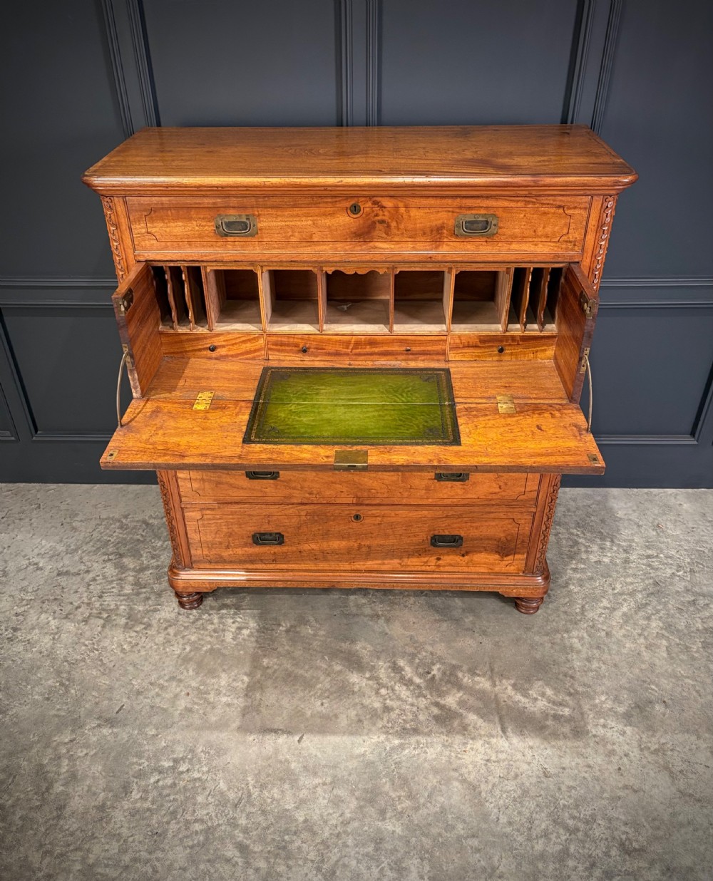 A 19th-century camphor wood campaign secretaire chest featuring a two-part split construction with flush brass handles, side carrying handles, and carved pilasters. View V