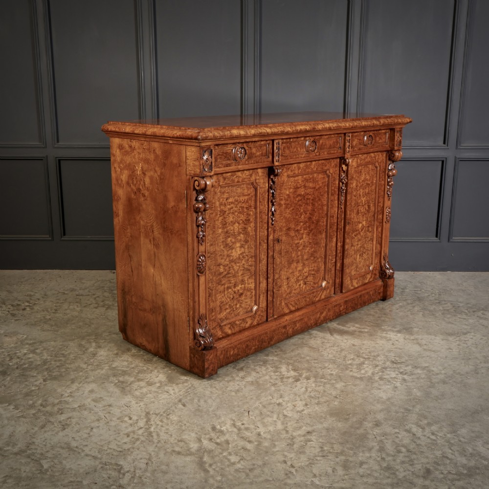 A Victorian pollard oak sideboard featuring three panelled cupboard doors, carved foliage pilasters, and a moulded rectangular top. View II