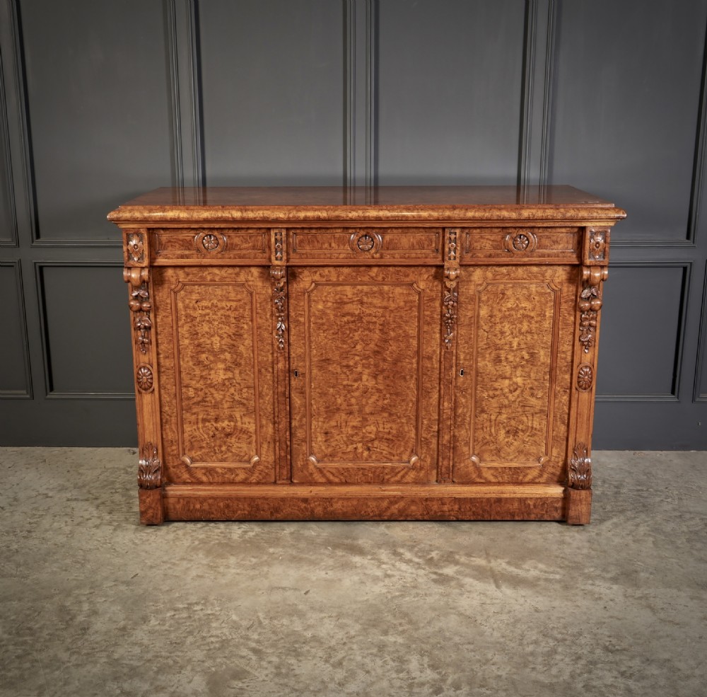 A Victorian pollard oak sideboard featuring three panelled cupboard doors, carved foliage pilasters, and a moulded rectangular top. View III