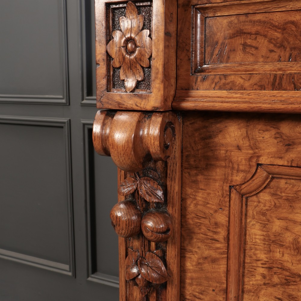 A Victorian pollard oak sideboard featuring three panelled cupboard doors, carved foliage pilasters, and a moulded rectangular top. View VII