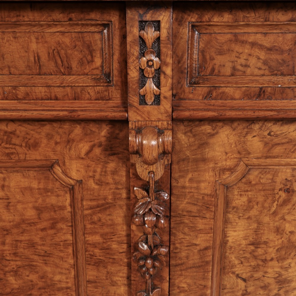 A Victorian pollard oak sideboard featuring three panelled cupboard doors, carved foliage pilasters, and a moulded rectangular top. View X