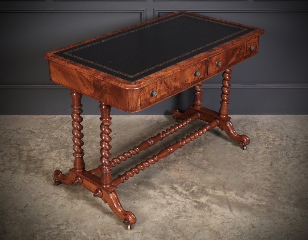 Victorian walnut library writing table with a black leather insert, barley twist legs, double spiral stretcher, and frieze drawers.