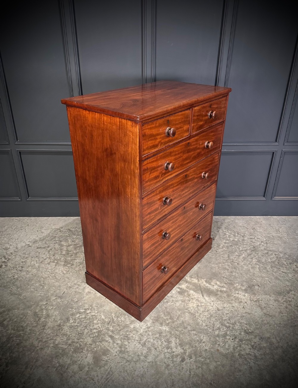A nineteenth-century Victorian mahogany chest of drawers featuring two short drawers over four long drawers with turned wooden handles on a plinth base. View V