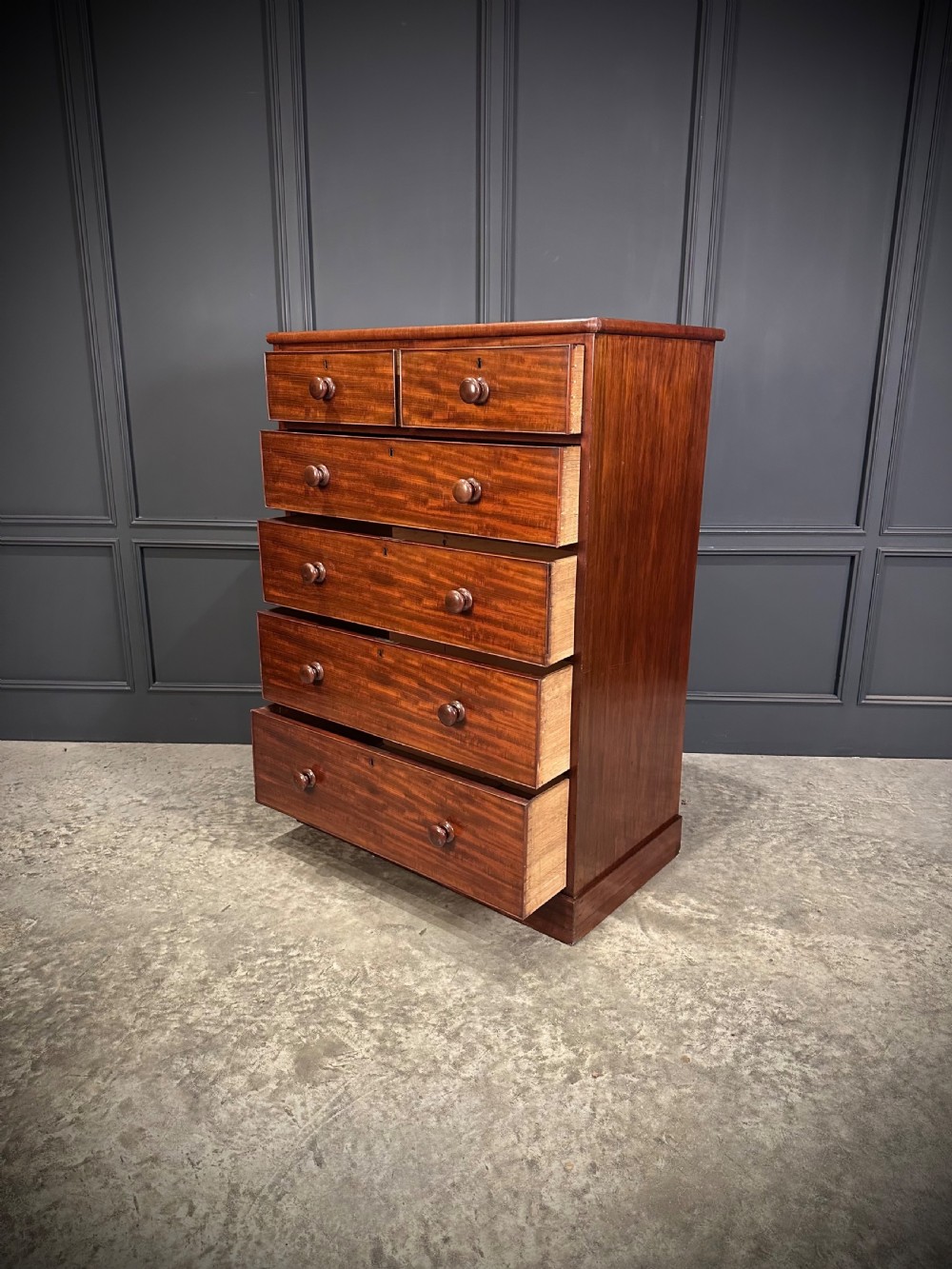 A nineteenth-century Victorian mahogany chest of drawers featuring two short drawers over four long drawers with turned wooden handles on a plinth base. View VI