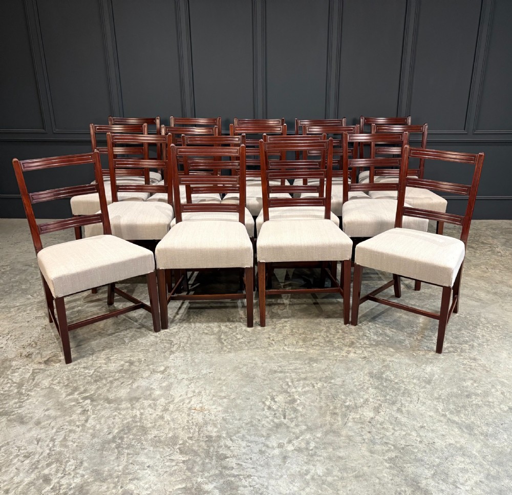 A set of eighteen Georgian mahogany dining chairs featuring triple horizontal bar backrests and light cream upholstered seats.