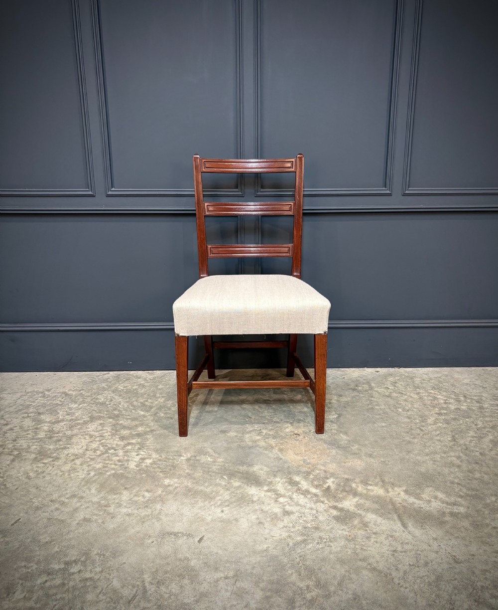 A set of eighteen Georgian mahogany dining chairs featuring triple horizontal bar backrests and light cream upholstered seats. View VI