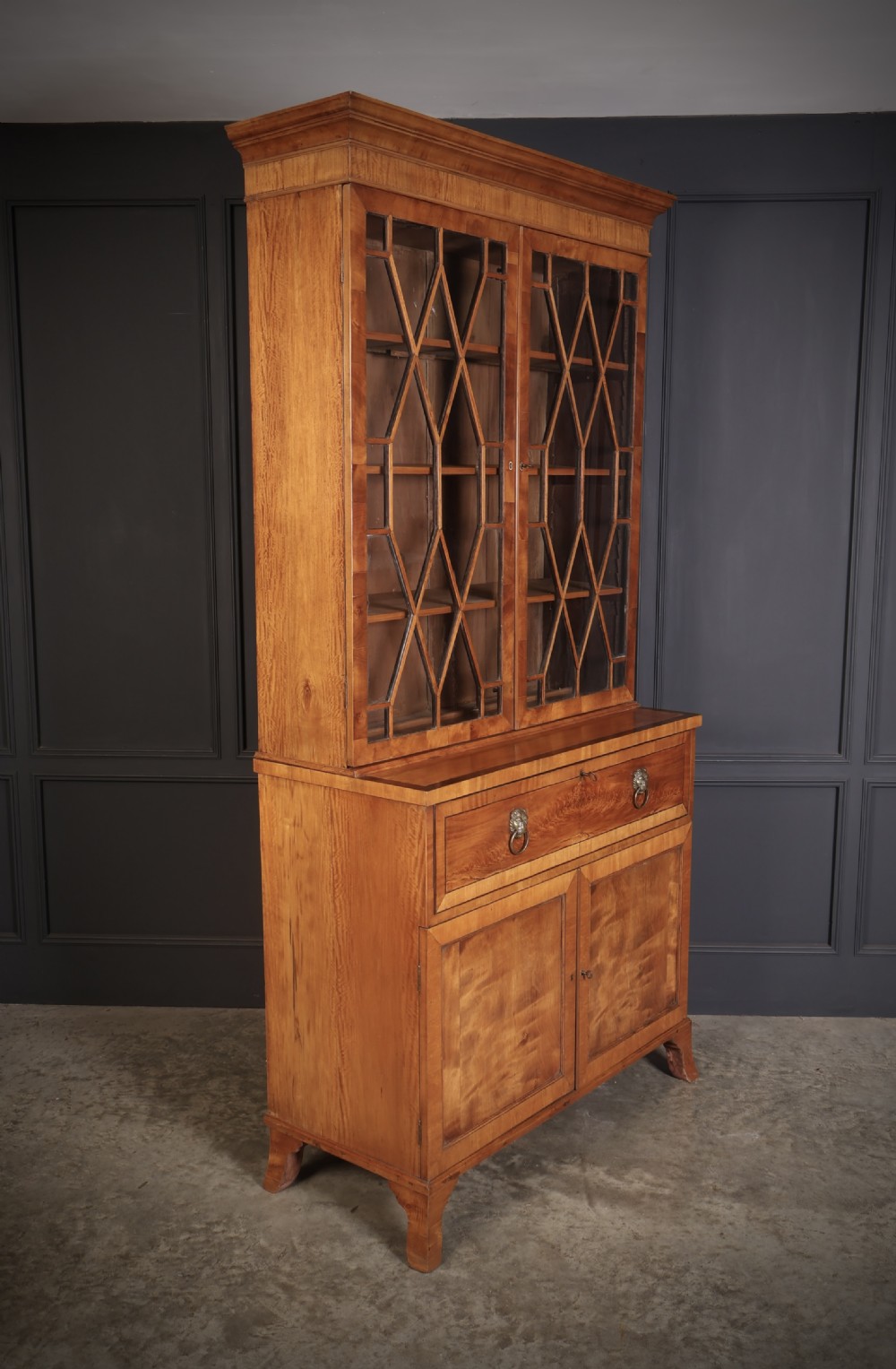 A Georgian satinwood secretaire bookcase with diamond astragal glazed doors above a lower cupboard base.