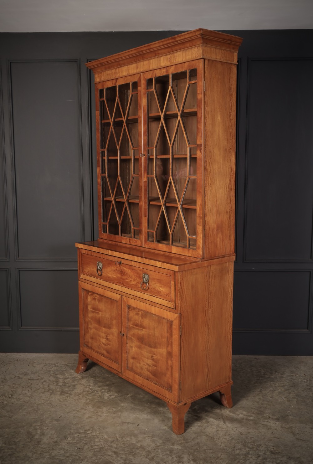 A Georgian satinwood secretaire bookcase with diamond astragal glazed doors above a lower cupboard base. View VI