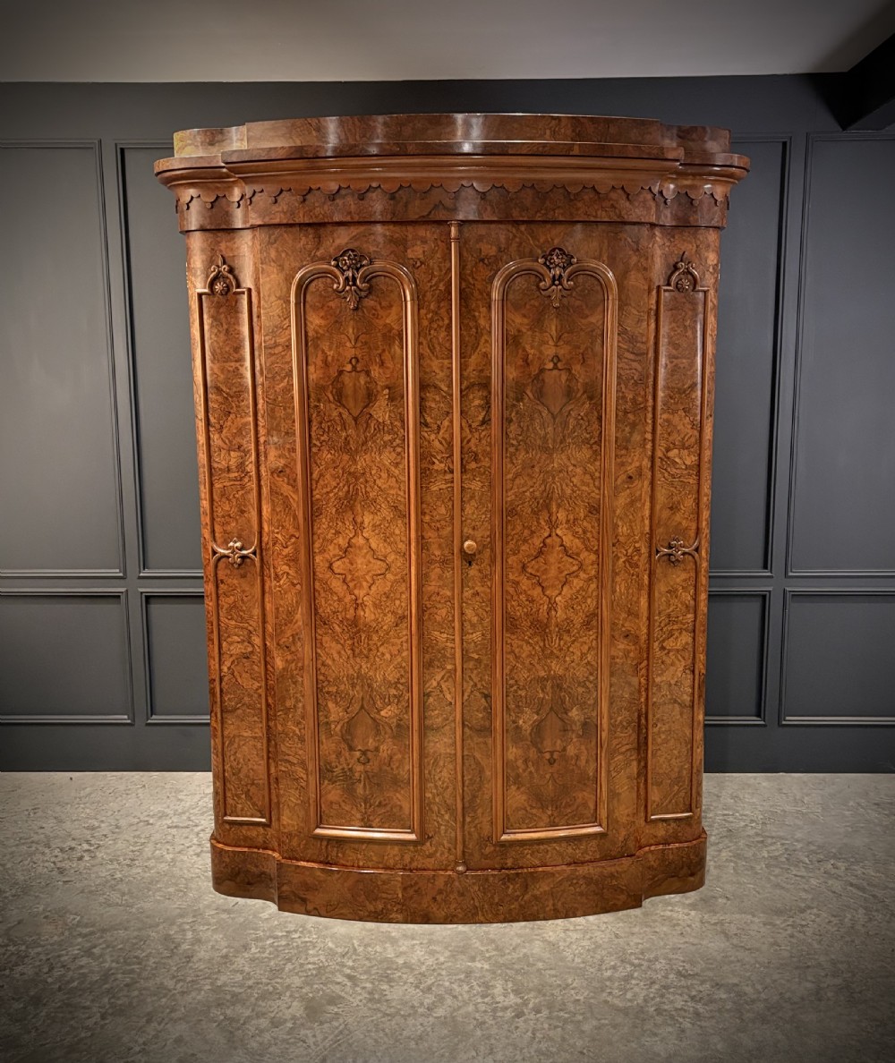 A large Victorian burr walnut bow-front wardrobe featuring carved arched door panels, a moulded cornice, and a plinth base. View II