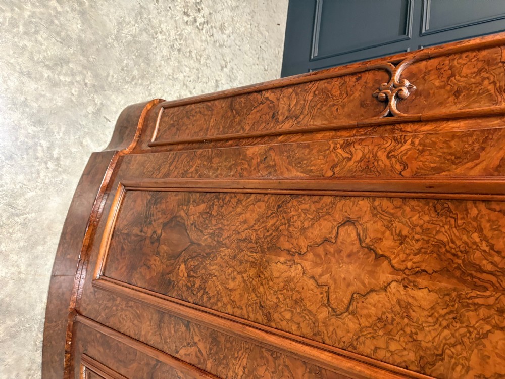 A large Victorian burr walnut bow-front wardrobe featuring carved arched door panels, a moulded cornice, and a plinth base. View III