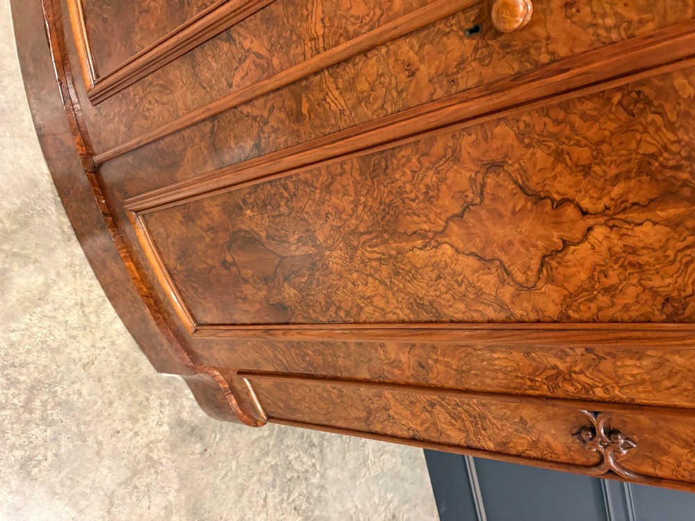 A large Victorian burr walnut bow-front wardrobe featuring carved arched door panels, a moulded cornice, and a plinth base. View IV