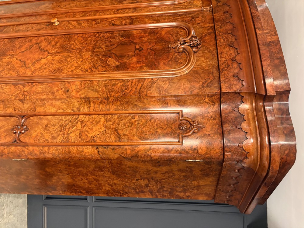A large Victorian burr walnut bow-front wardrobe featuring carved arched door panels, a moulded cornice, and a plinth base. View VII