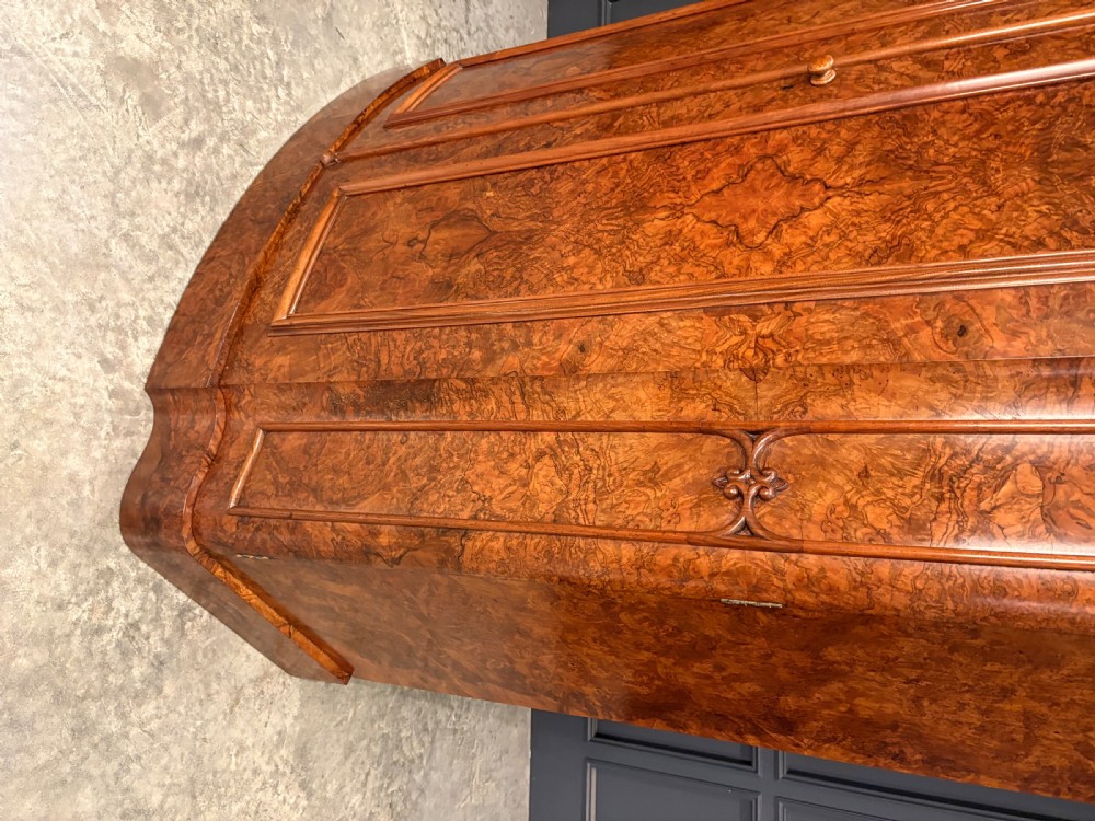 A large Victorian burr walnut bow-front wardrobe featuring carved arched door panels, a moulded cornice, and a plinth base. View VIII