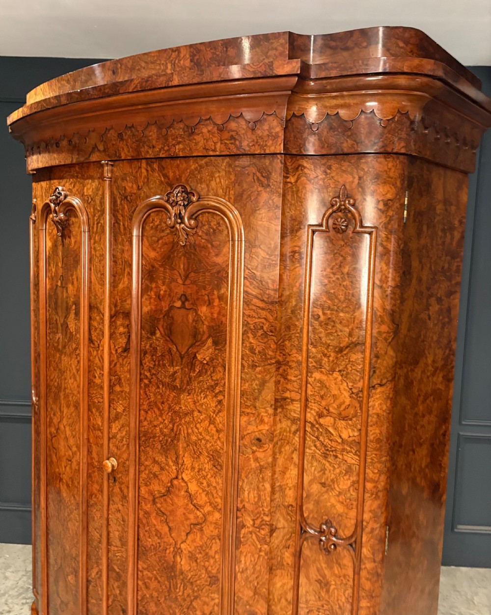 A large Victorian burr walnut bow-front wardrobe featuring carved arched door panels, a moulded cornice, and a plinth base. View IX