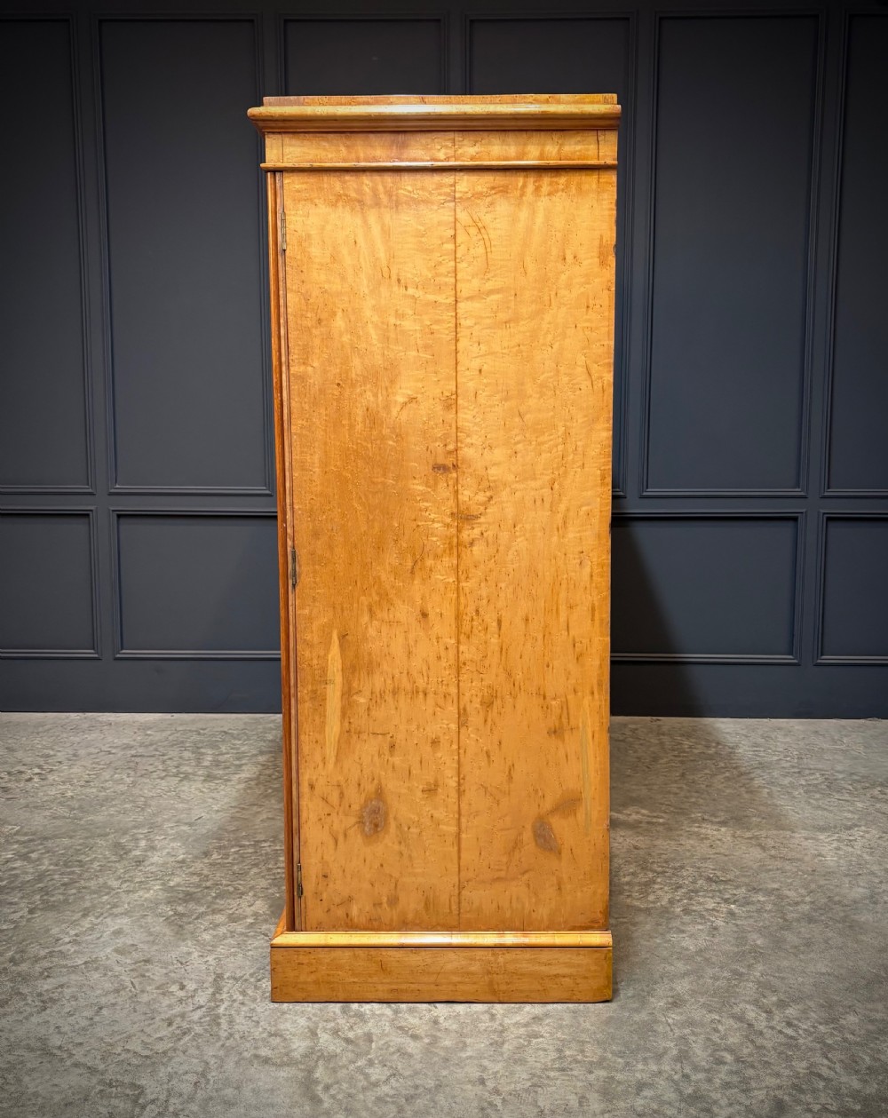 A low Victorian three-door wardrobe crafted from birds eye maple featuring dark wood inlaid borders and turned wooden knobs. View V