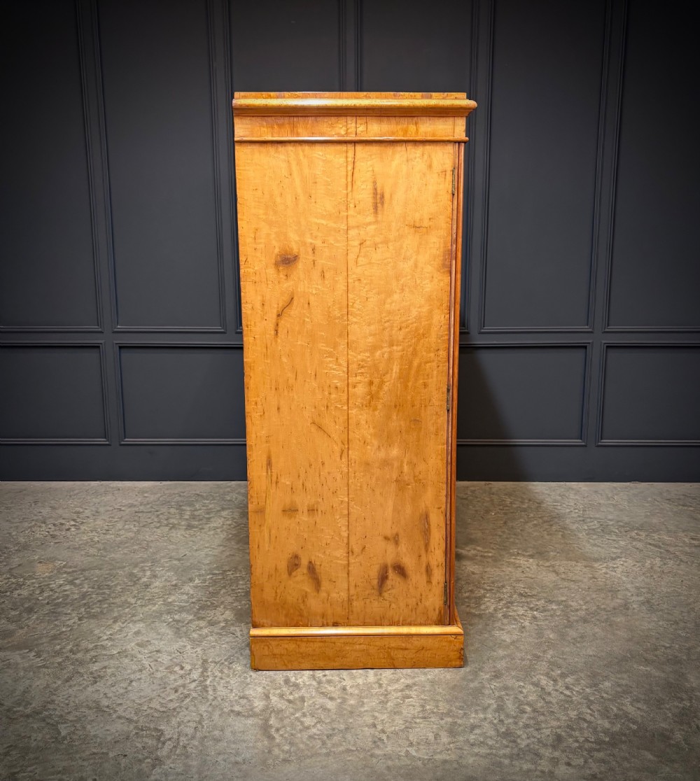 A low Victorian three-door wardrobe crafted from birds eye maple featuring dark wood inlaid borders and turned wooden knobs. View IV