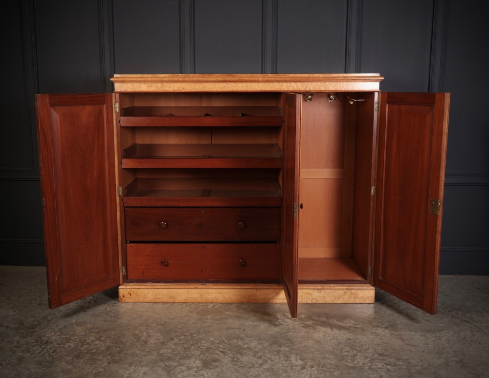 A low Victorian three-door wardrobe crafted from birds eye maple featuring dark wood inlaid borders and turned wooden knobs. View VII