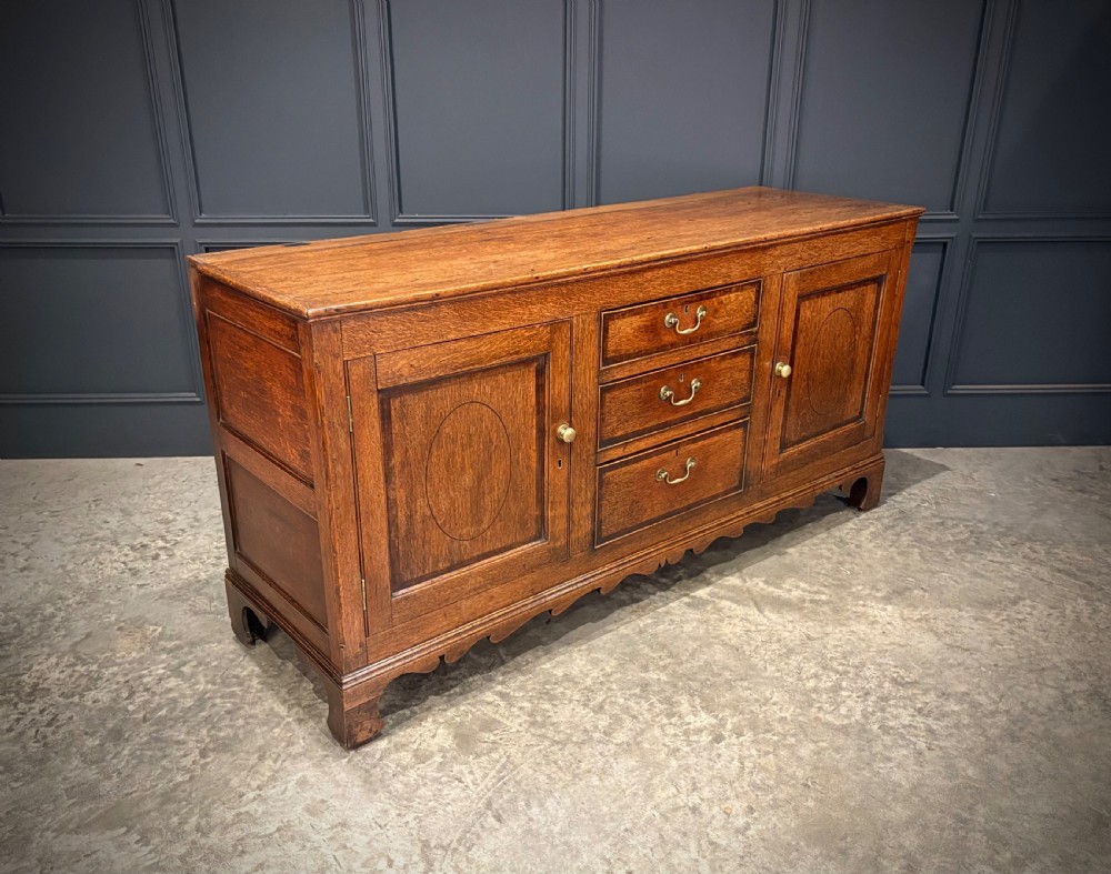 An eighteenth-century oak welsh dresser featuring a three-shelf open upper rack and a lower base with three drawers and two panelled cupboard doors. View II