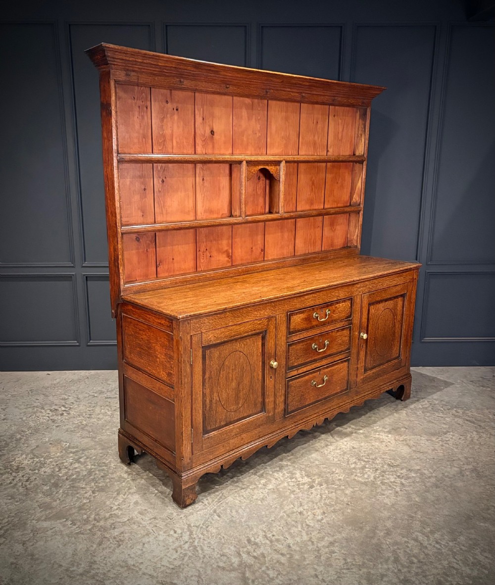 An eighteenth-century oak welsh dresser featuring a three-shelf open upper rack and a lower base with three drawers and two panelled cupboard doors. View III