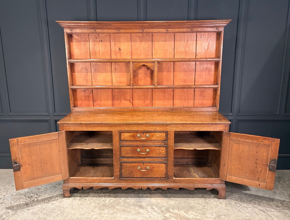 An eighteenth-century oak welsh dresser featuring a three-shelf open upper rack and a lower base with three drawers and two panelled cupboard doors. View VI