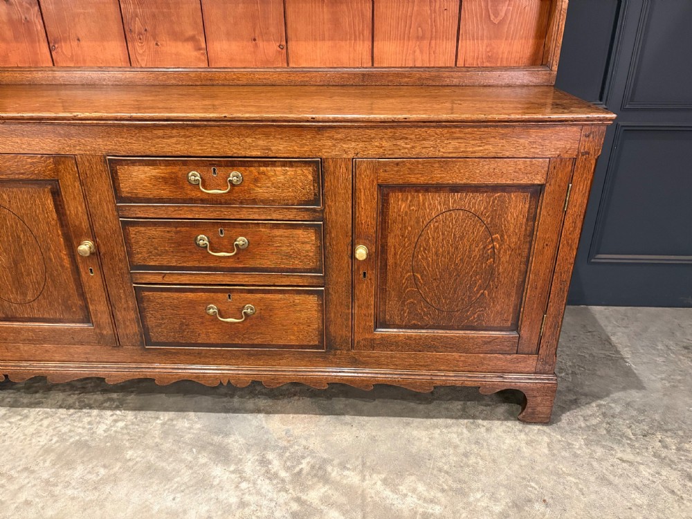 An eighteenth-century oak welsh dresser featuring a three-shelf open upper rack and a lower base with three drawers and two panelled cupboard doors. View VII