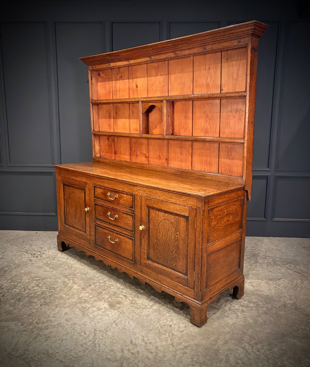 An eighteenth-century oak welsh dresser featuring a three-shelf open upper rack and a lower base with three drawers and two panelled cupboard doors. View XI