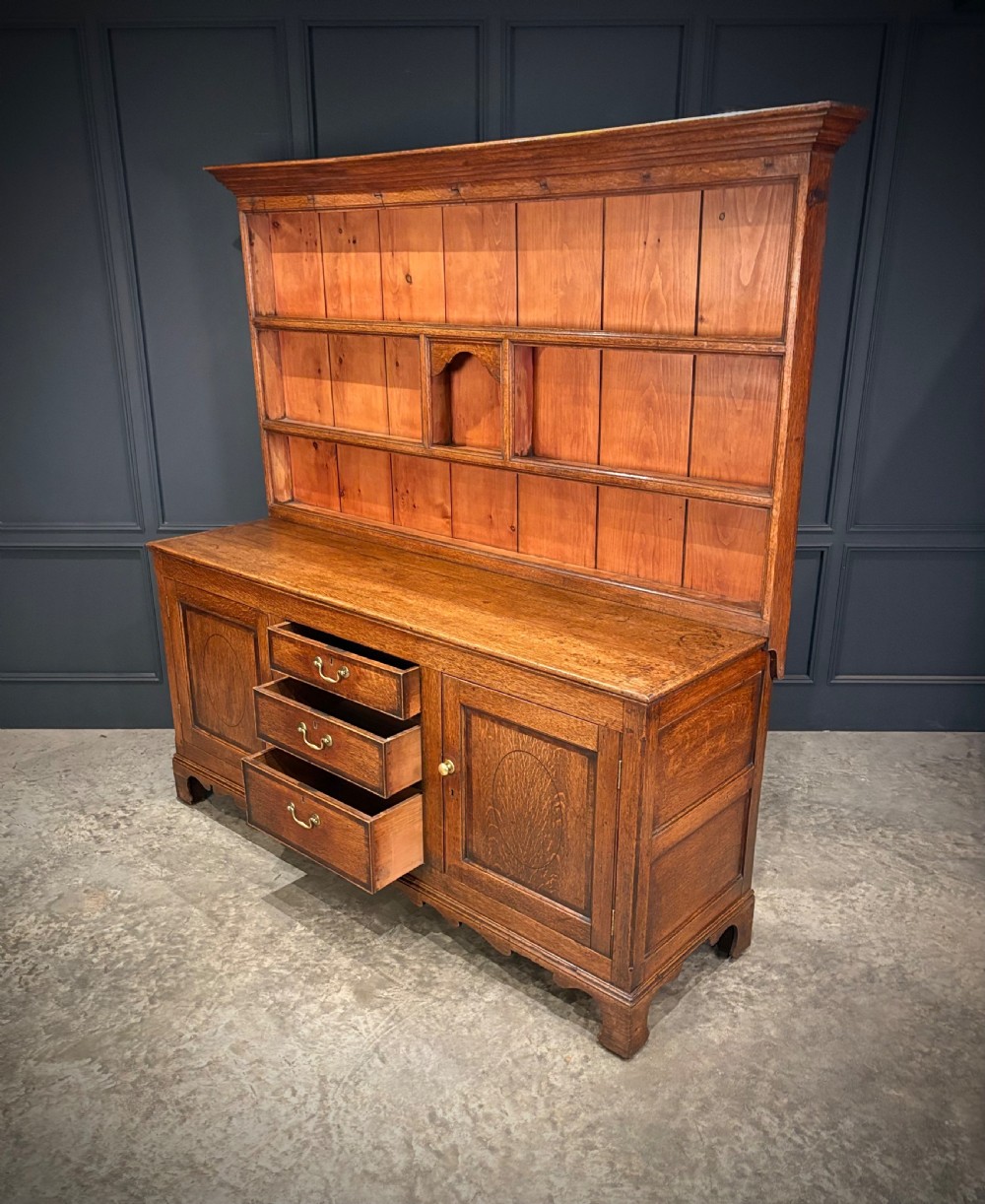 An eighteenth-century oak welsh dresser featuring a three-shelf open upper rack and a lower base with three drawers and two panelled cupboard doors. View XII
