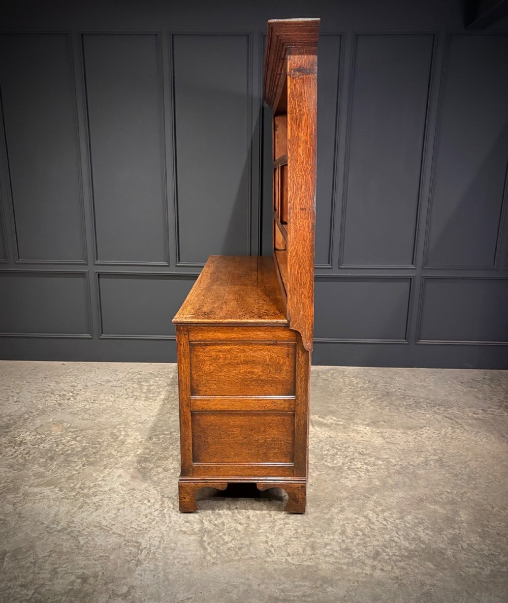 An eighteenth-century oak welsh dresser featuring a three-shelf open upper rack and a lower base with three drawers and two panelled cupboard doors. View XIII