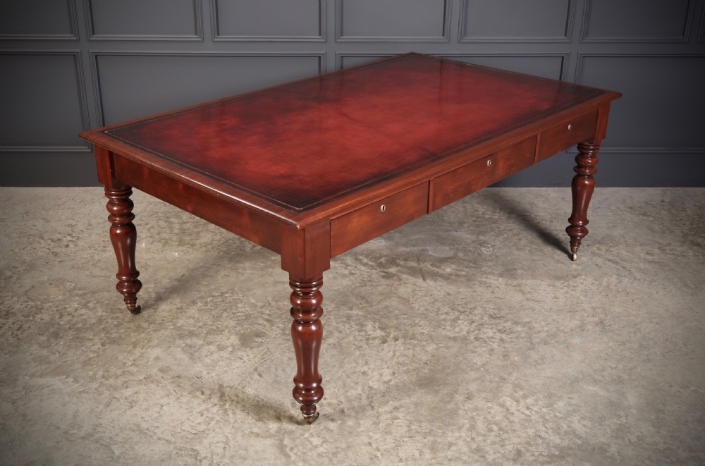 A Victorian mahogany partners writing table with a rich red leather inlaid top, frieze drawers, and turned legs set on brass castors.