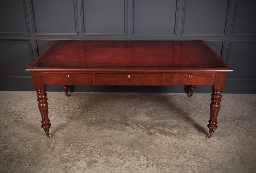 A Victorian mahogany partners writing table with a rich red leather inlaid top, frieze drawers, and turned legs set on brass castors. View II