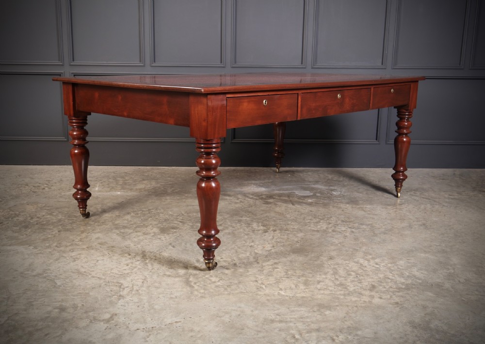 A Victorian mahogany partners writing table with a rich red leather inlaid top, frieze drawers, and turned legs set on brass castors. View III