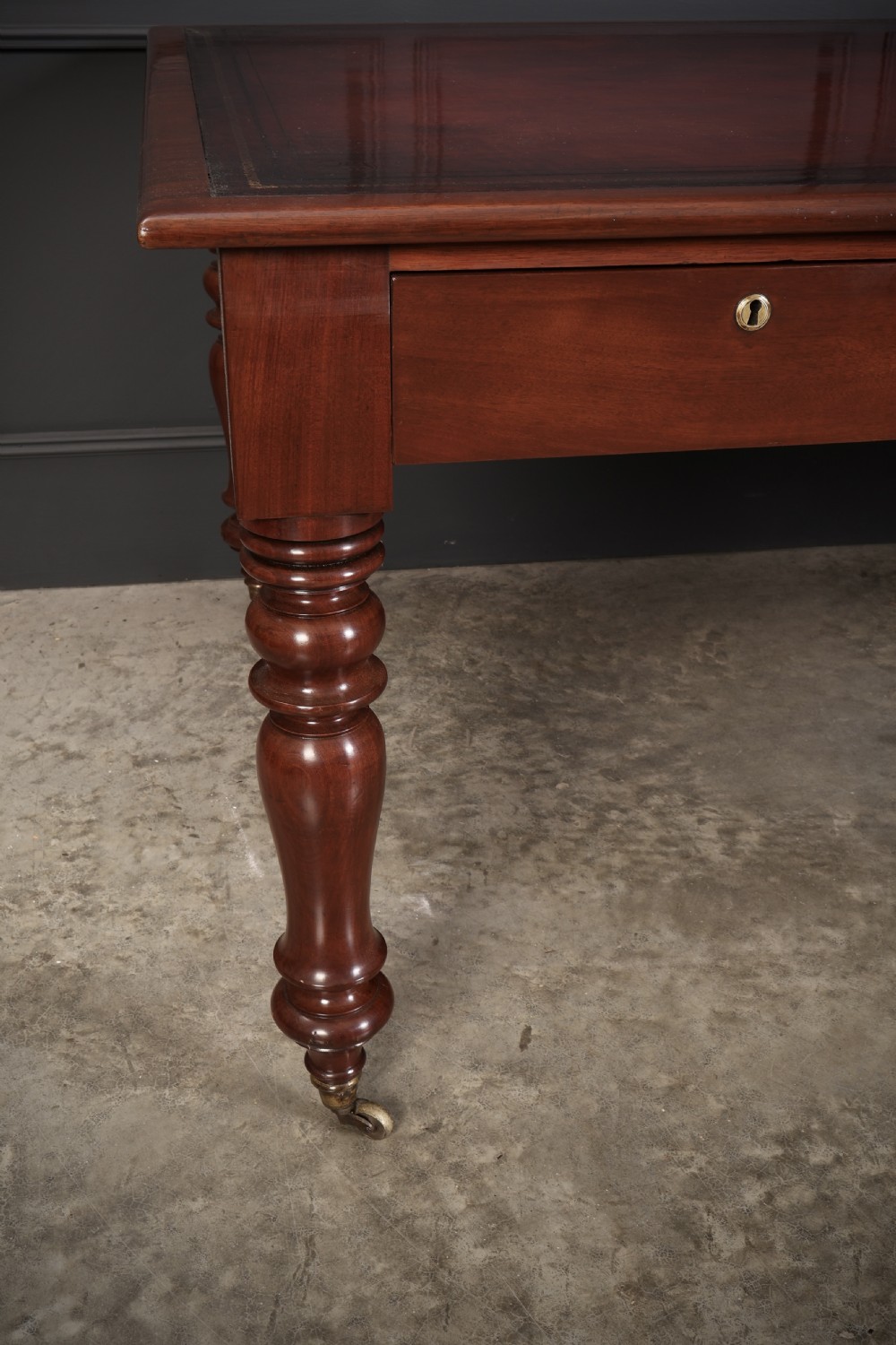 A Victorian mahogany partners writing table with a rich red leather inlaid top, frieze drawers, and turned legs set on brass castors. View VI