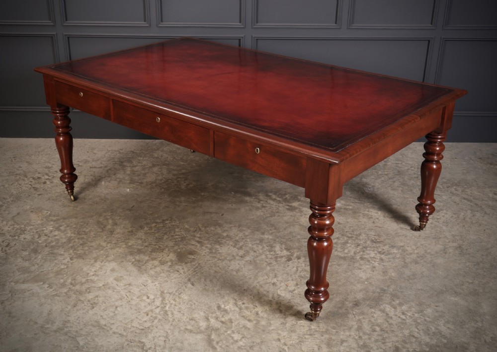 A Victorian mahogany partners writing table with a rich red leather inlaid top, frieze drawers, and turned legs set on brass castors. View VII