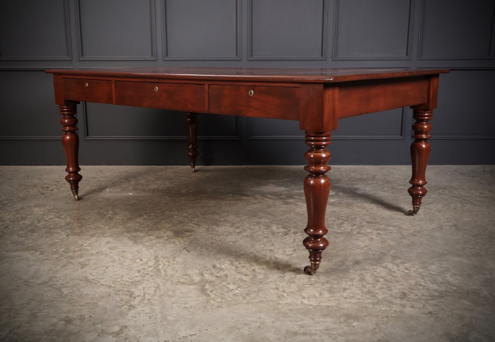 A Victorian mahogany partners writing table with a rich red leather inlaid top, frieze drawers, and turned legs set on brass castors. View VIII
