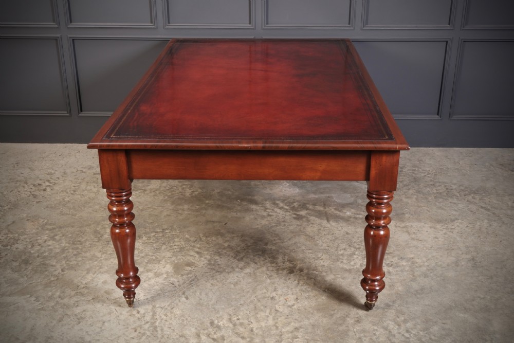 A Victorian mahogany partners writing table with a rich red leather inlaid top, frieze drawers, and turned legs set on brass castors. View X